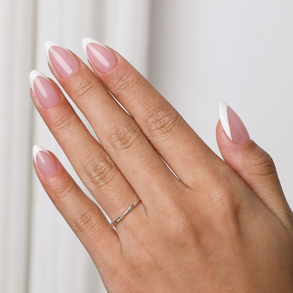 Short almond press-on nails with a soft pink base and classic French tips